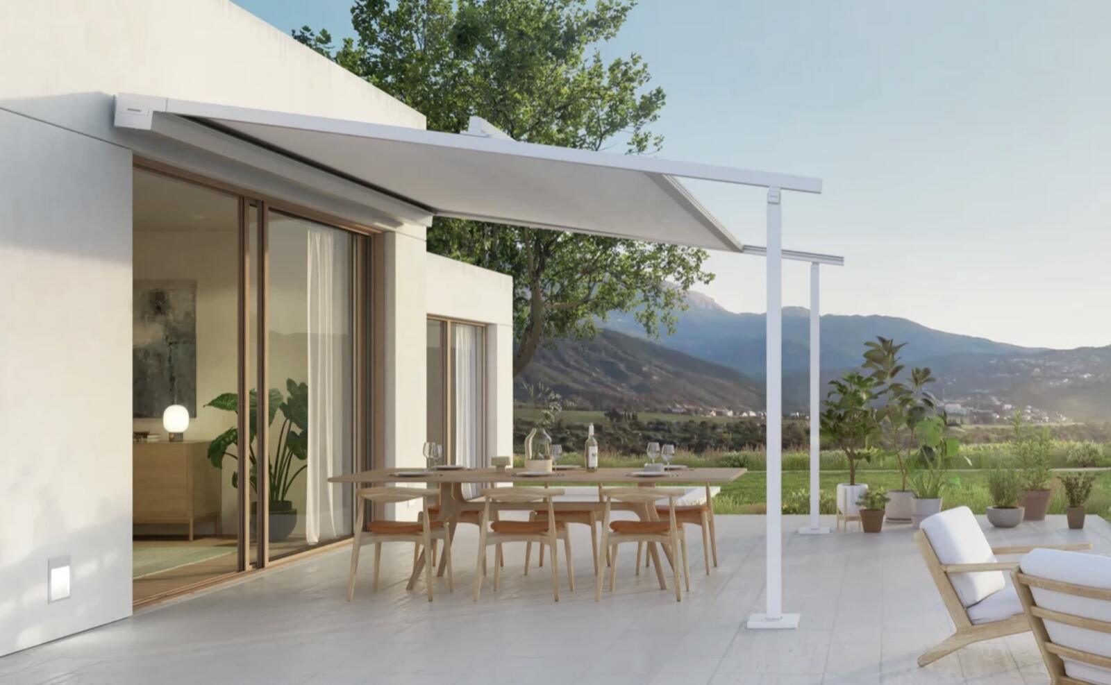 Freitragende Pergolamarkise in Hellgrau über einer modernen Terrasse mit gedecktem Esstisch und Panoramablick auf Berge