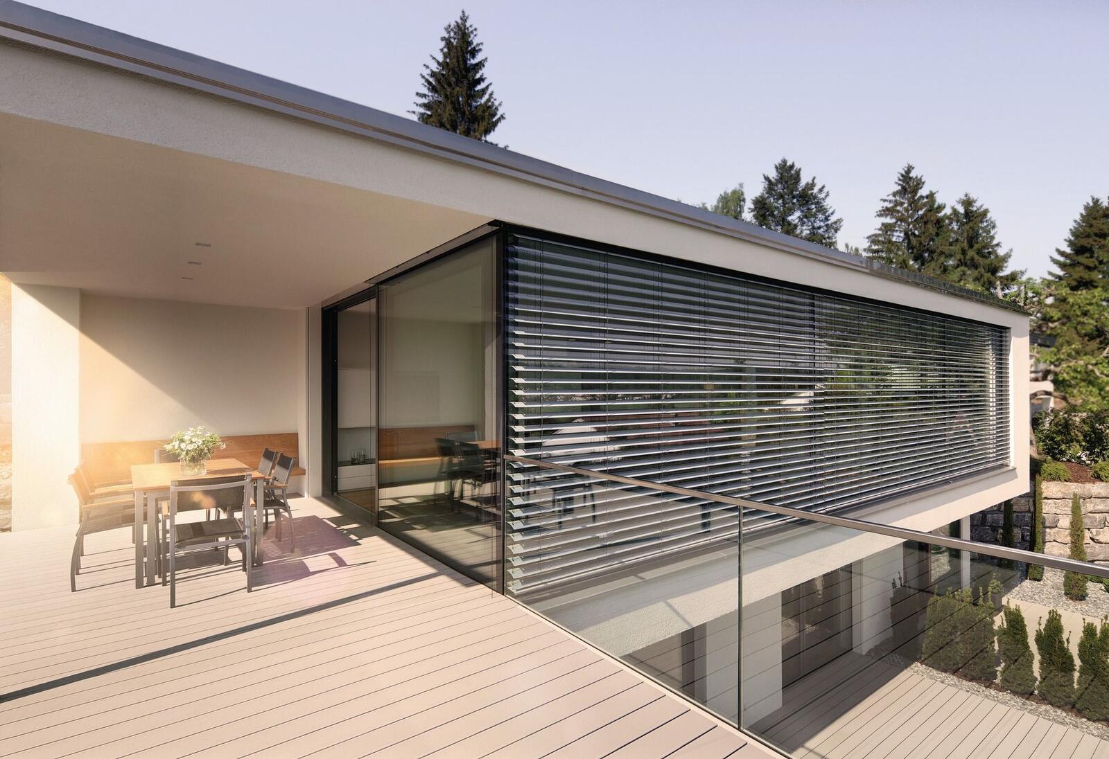 Außenliegender Raffstore an moderner Villa mit Terrasse — horizontale Aluminiumlamellen in Dunkelgrau